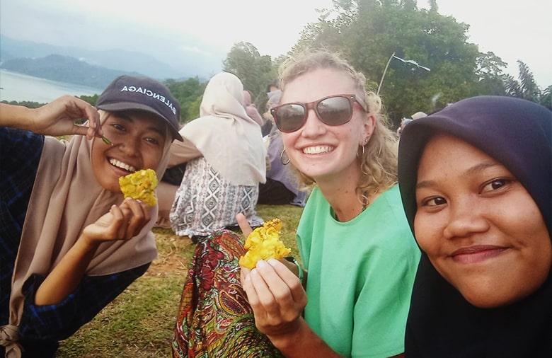 Alina mit zwei Freundinnen bei einem Selfie. Sie halten Essen in der Hand.