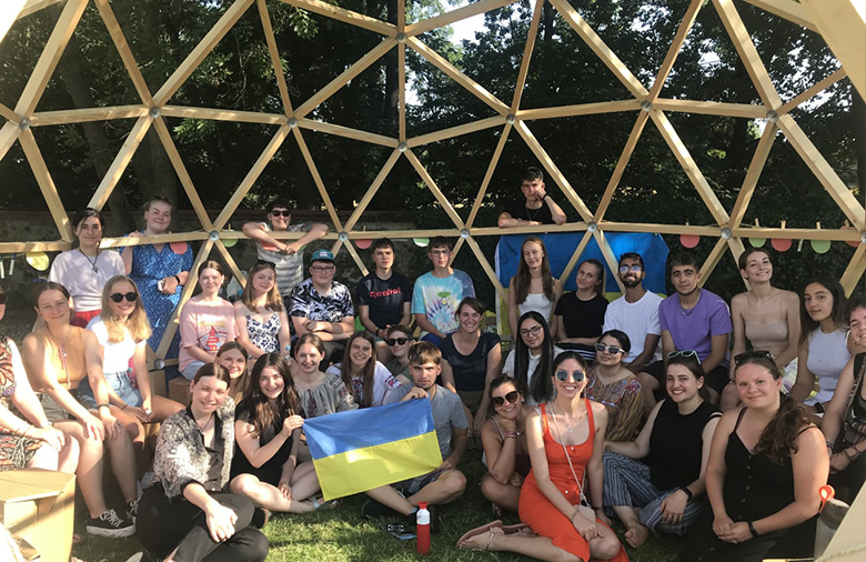 Eine Gruppe von jungen Menschen unter einer Kuppel aus Holz.