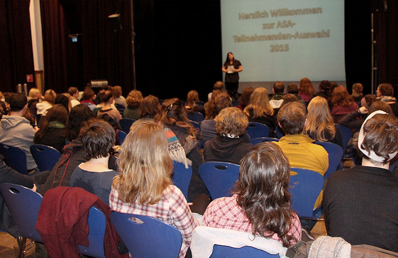 In einem großen Veranstaltungsaal schaut das Publikum der Präsentation und Erklärung auf der Bühne zu. Foto: Miriam Eckert.
