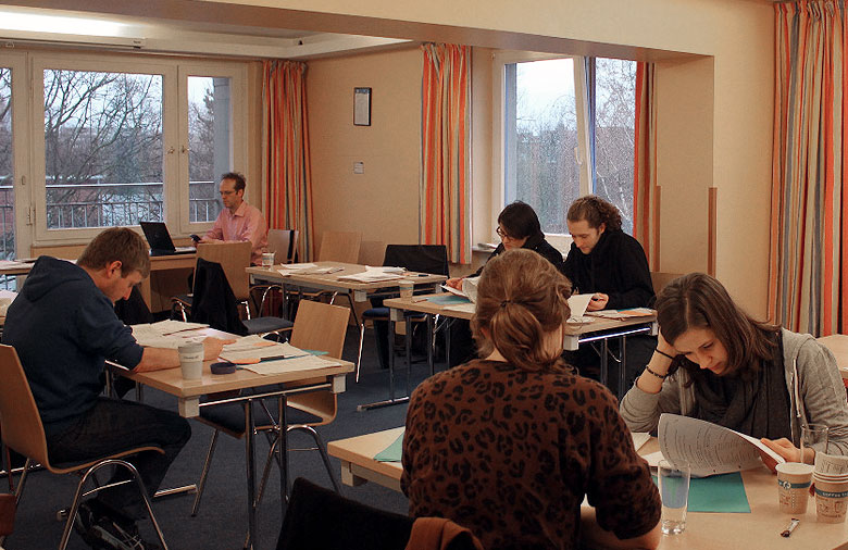 Das Bild zeigt einen Raum mit mehreren Tischen, an denen jeweils ein bis zwei Personen lesen und sich unterhalten. Foto: Mira Schönegge