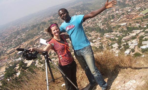 Daniela Schaffart und ihr Projektpartner Basil Azah Azefor stehen auf einer Erhöhung über einer Stadt, die im Hintergrund zu erkennen ist. Daniela hat eine Kamera in der Hand, die auf einem Stativ befestigt ist. Foto: Daniela Schaffart.