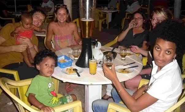 Eine Gruppe Erwachsene und Kinder isst gemeinsam am Strand zu Abend. Foto: Lena Geske