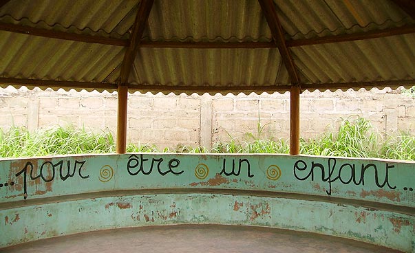 Auf der Innenwand eines Gebäudes mit offenen Seiten steht „pour etre un enfant“ geschrieben.  Foto: Charly Heberer.