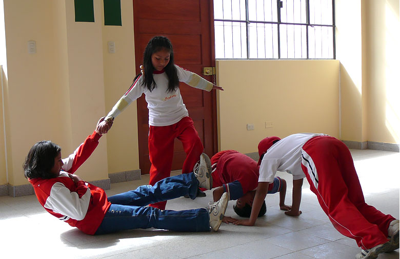 Vier Kinder und Jugendliche bewegen sich in einem Raum. Sie tragen rote und weiße Kleidung. Foto: Nina Horn