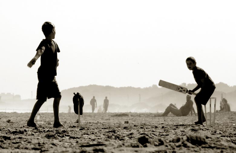 Zwei Jungen spielen an einem Strand Cricket. Foto: Sarah Piel