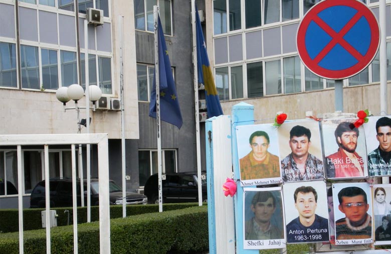 Das Regierungsgebäude in Pristina ist im Hintergrund zu sehen. Davor steht ein Zaun mit Fotos der Vermissten Personen. Foto: Muhamet Idrizi