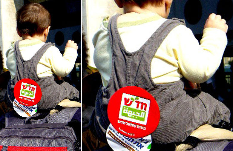 Ein Kleinkind, welches auf den Schultern eines Erwachsenen getragen wird, ist von hinten zu sehen. Auf seinem Rücken ist der „Khadash“-Aufkleber platziert. Foto: Ruth Mosser