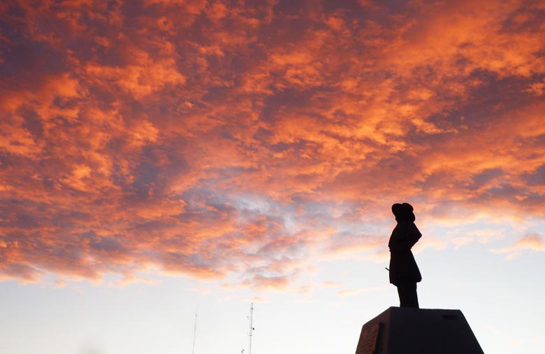 Der rot-orange erleuchtete Himmel bei Sonnenuntergang ist zu sehen. In der unteren rechten Bildhälfte zeichnet sich eine Statue. Foto: Katharina Storch