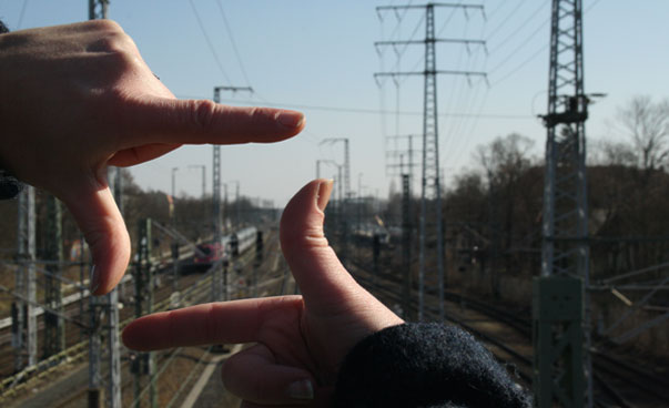 Zwei Hände bilden einen Fotorahmen. Im Hintergrund ist ein Zug zu sehen.
