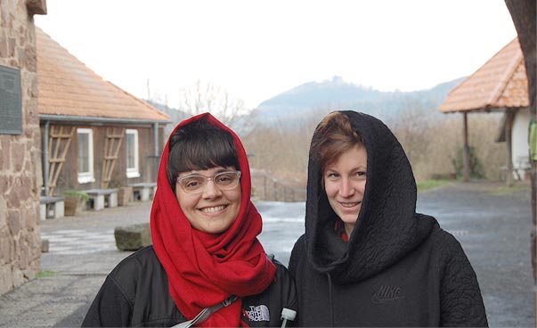 Two persons with hoods smile into the camera.