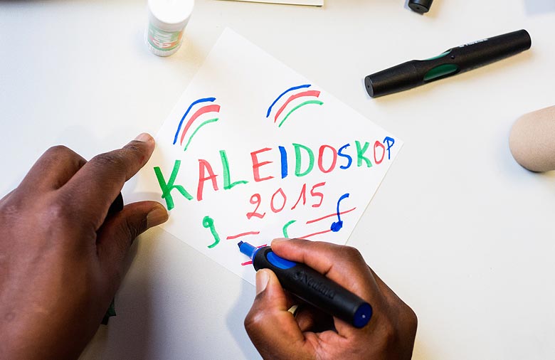 Eine Hand hält einen Stift und schreibt den Schriftzug „Kaleidoskop 2015“. Foto: Jule Roehr.