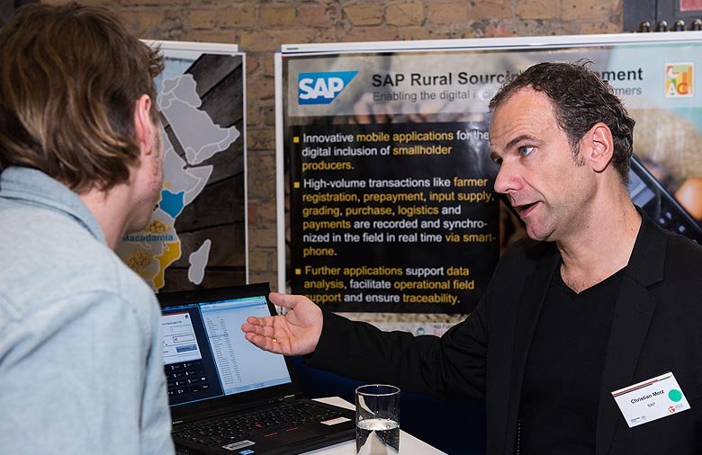 Christian Merz von SAP unterhält sich mit einem Teilnehmenden und zeigt ihm etwas auf einem Laptop. Foto: Jule Roehr.